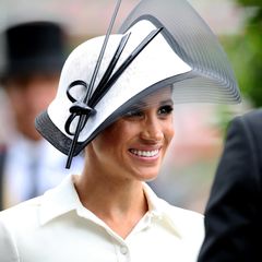 Beim Royal Ascot Pferderennen verzaubert Herzogin Meghan in einem weißen Midikleid von Givenchy, zu welchem sie schlichte schwarze Pumps kombiniert. Der Hut ist natürlich farblich auf das Kleid abgestimmt. Kurz: Die perfekte Wahl angesichts des strengen Dresscodes beim Royal Ascot. Der Philip Treacy Fascinator steht der jungen Herzogin ganz fantastisch. Ob Zufall oder nicht - das schwarz-weiße Outfit erinnert an jenes berühmte Ensemble, welches Audrey Hepburn 1964 beim Besuch eines Pferderennens im Kultmusical "My Fair Lady" trägt. 