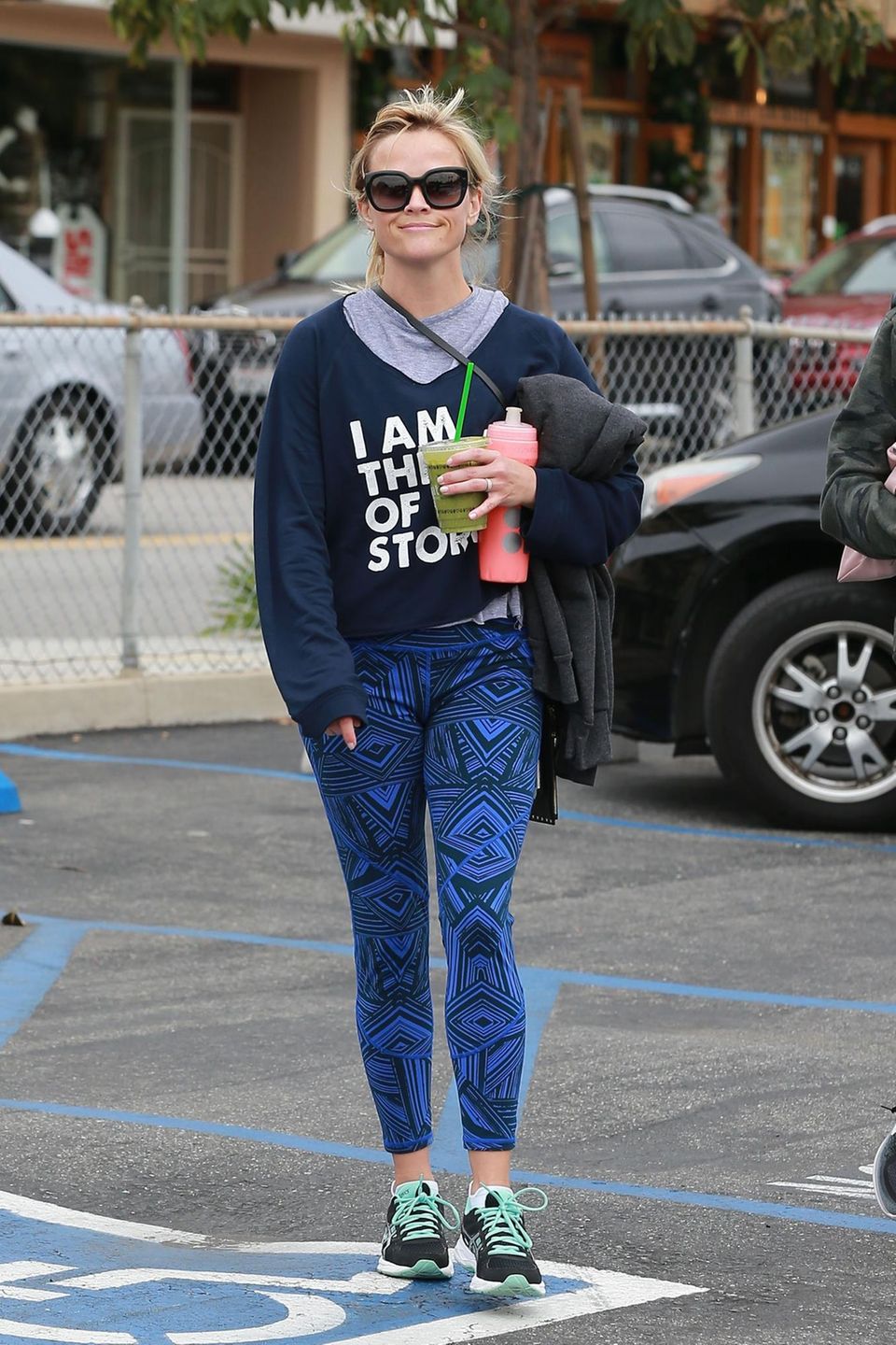 Reese Witherspoon mixt ganz schön wild: Zum Slogan-Sweater kommt bei ihr eine Hose mit Aztekenmuster und Sneaker mit Neon-Schnürsenkeln.