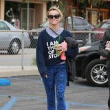 Reese Witherspoon mixt ganz schön wild: Zum Slogan-Sweater kommt bei ihr eine Hose mit Aztekenmuster und Sneaker mit Neon-Schnürsenkeln.