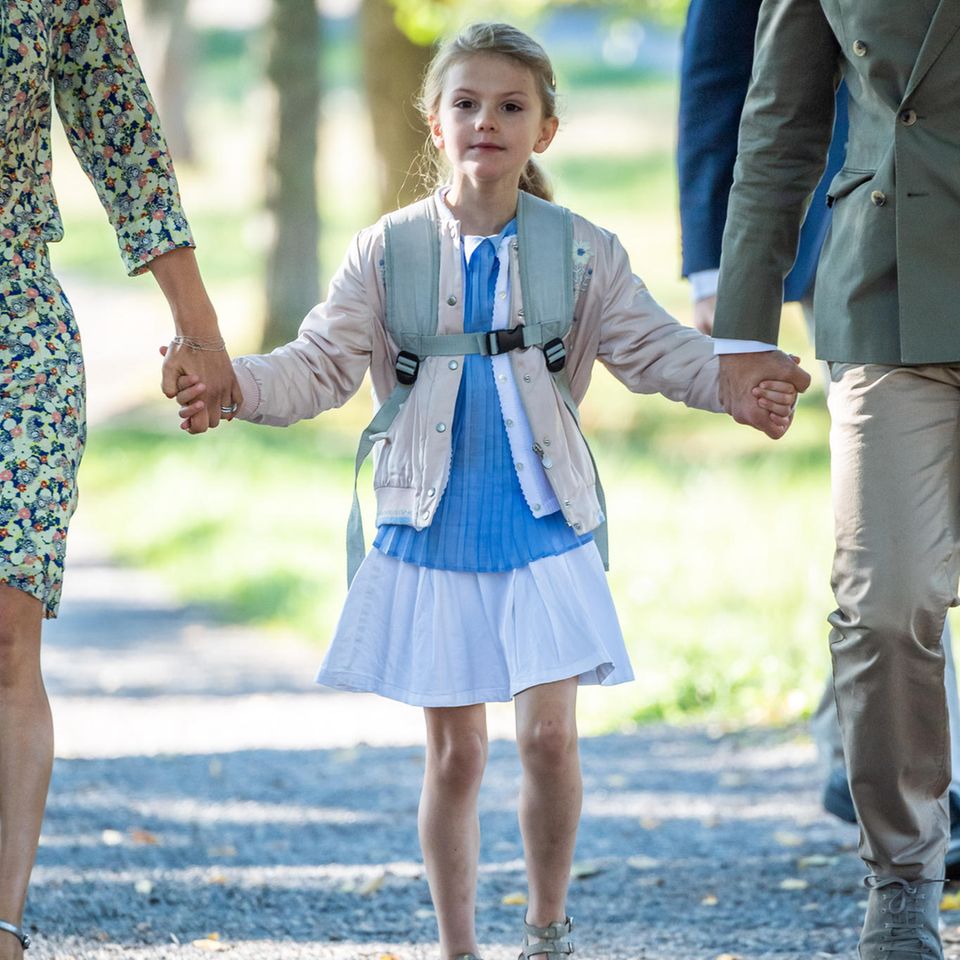 Am Tag ihrer Einschulung zeigt sich Prinzessin Estelle von ihrer besten Seite. Zum weißen Röckchen trägt sie ein Plissé-Oberteil mit Bubi-Kragen und eine weiße leichte Strickjacke. Cooler wird der Schulmädchenlook durch eine Bomberjacke.