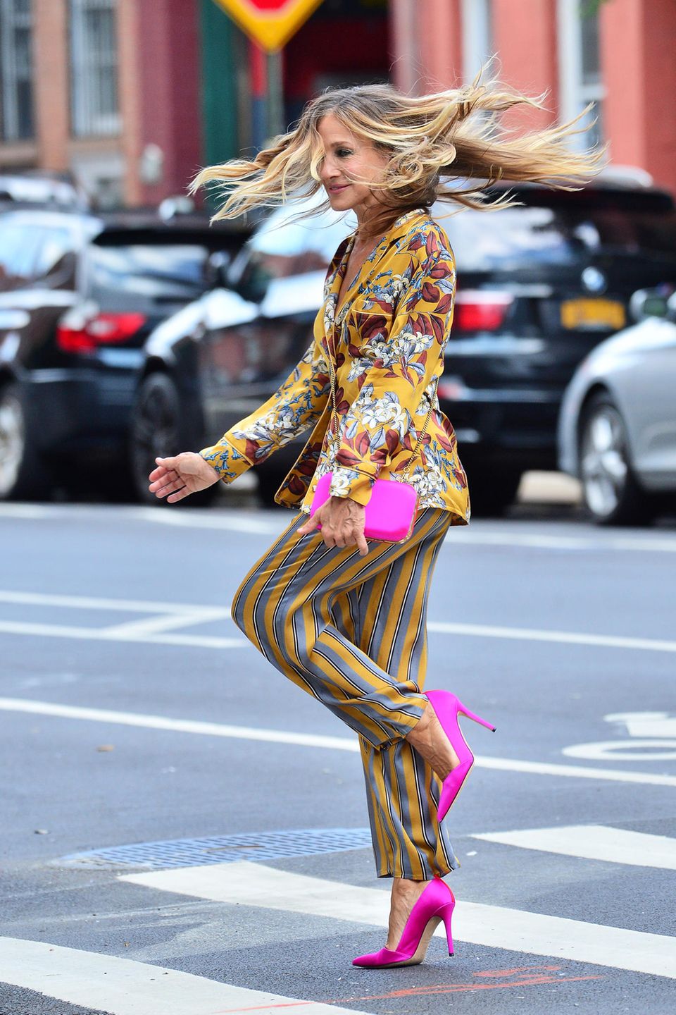 Die Schauspielerin dreht eine Pirouette und lässt dabei ihre Haare fliegen. Zum Mustermix im Pyjama-Stil von "Intimissimi" kombiniert Sarah Jessica Parker pinkfarbene Accessoires in Form einer Clutch und spitzen Pumps. Ein echter Hingucker! 