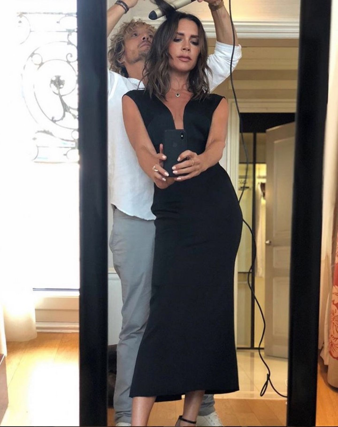 Für ein Selfie ist doch immer Zeit. Modeikone Victoria Beckham schießt ein schnelles Foto, während ihr Stylist sich um die Haare kümmert. 