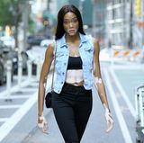 Model Winnie Harlow auf dem Weg zum Callback. Sie kombiniert eine schwarze Jeans zum knappen Bandeau-Top und lässiger Jeans-Weste. Schnürstiefel in schwindelerregender Höhe runden ihren Casting-Look ab. 