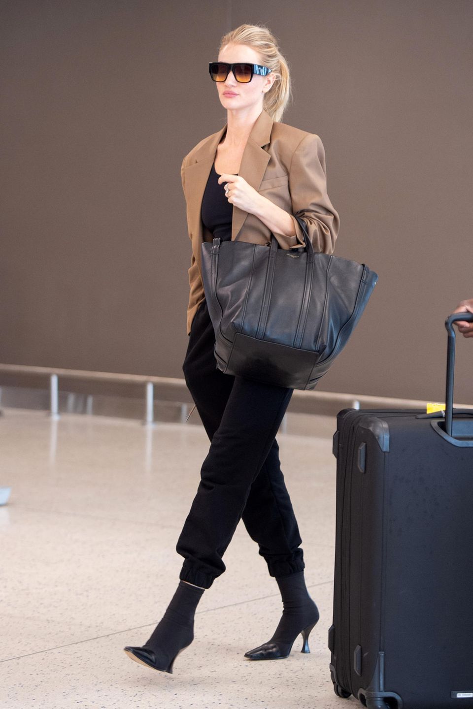 So elegant wie Rosie Huntington-Whiteley hat wohl noch niemand eine Jogginghose getragen. Am JFK-Flughafen in New York lichten Paparazzi das Supermodel genau mit einer solchen ab. Dazu kombiniert die Fashionista Stiefeletten und ein bequemes Shirt – alles in Schwarz. Lediglich der schicke und kamelfarbene Blazer erhellt das Outfit.