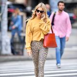 Sienna Miller zeigt, wie man den Leo-Trend ganz simpel im Alltag tragen und kombinieren kann. Zu einer Hose mit Leo-Print kombiniert sie einen farblich harmonierenden Pullover und setzt mit einer roten Handtasche Akzente. 