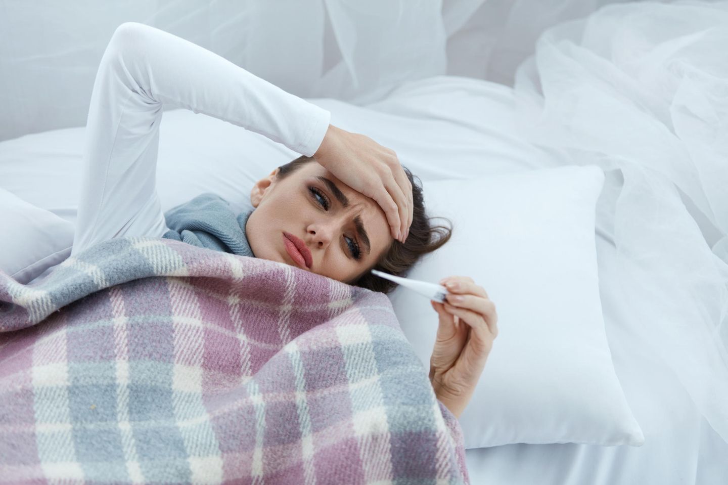 Frau mit Fieber im Bett (Symbolbild)