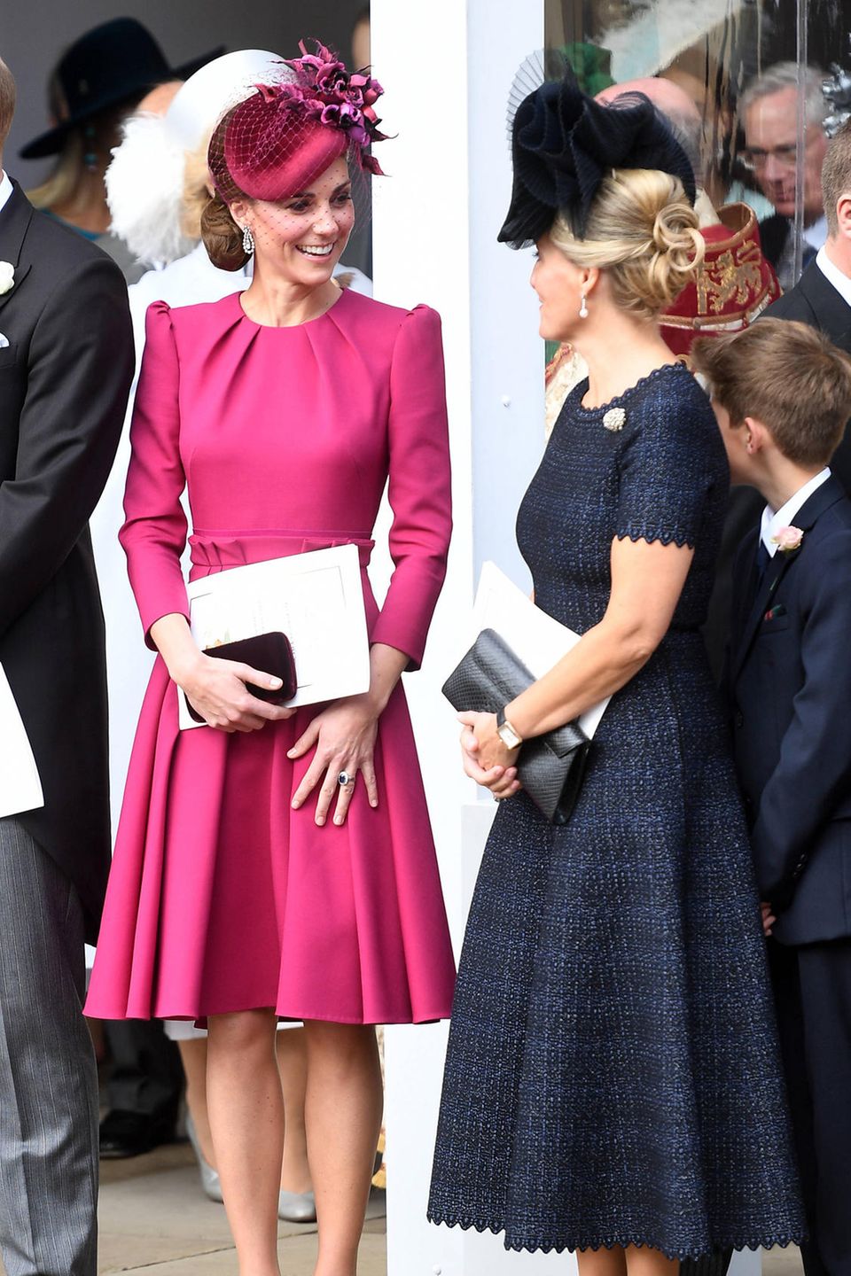 Zu ihrem leuchtenden Dress von Alexander McQueen kombiniert die schöne Ehefrau von Prinz William einen farblich abgestimmten Fascinator und eine bordeauxfarbene Clutch, sowie passende High Heels. 