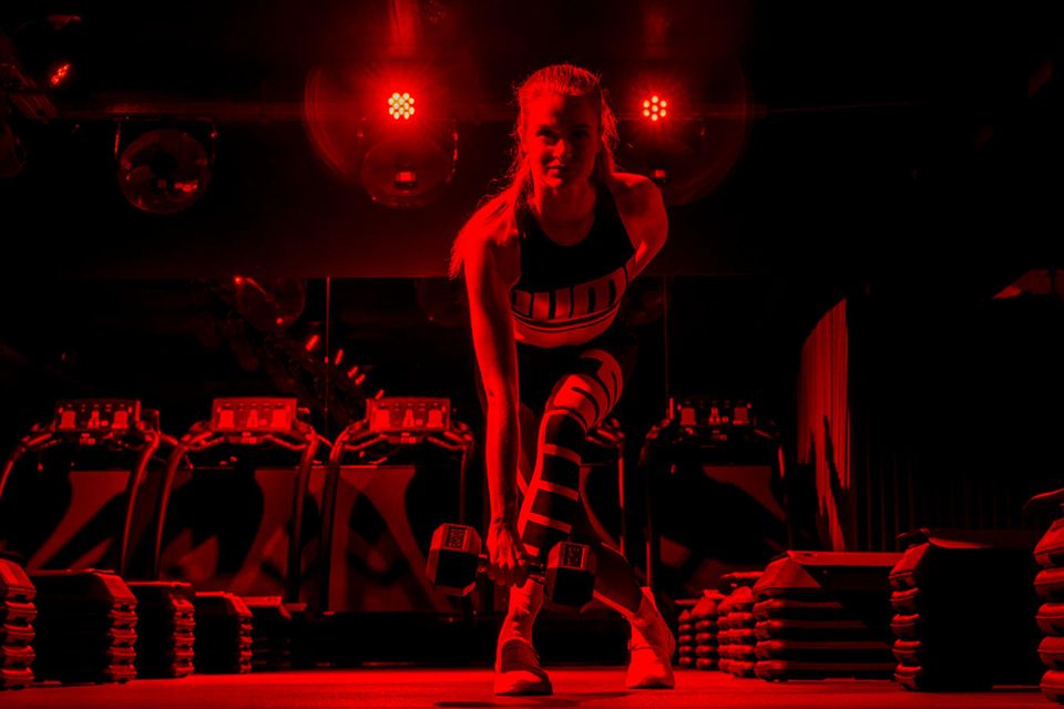 Im Urban Heroes in Hamburg ist der Raum in rotes Licht getaucht, die Musik spielt laut aus den Boxen. Die Atmosphäre reißt Tabea mit. An den Steps bringt sie mit Gewichten ihre Muskeln zum Glühen.