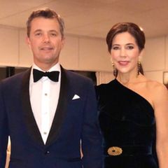 Prinz Frederik und Prinzessin Mary lassen es sich nicht nehmen, den 70. Geburtstag von Prinz Charles in London zu feiern. Für das Dinner wählt Mary ein langes One-Shoulder-Abendkleid aus dunkelblauem Samt. Ihre Taille wird durch einen gleichfarbigen Gürtel mit einer goldenen Brosche betont, den Brustbereich verzieren Volants. In Sachen Schmuck setzt die dänische Kronprinzessin auf lange Ohrringe und passende Armbänder, die Haare trägt sie hochgesteckt. Prinz Frederik wählt einen klassischen Smoking, passt sich aber der Farbwahl seiner Ehefrau an. Das royale Paar gibt sich zu diesem Anlass überraschend privat - Händchen haltend strahlen sie in die Kamera.