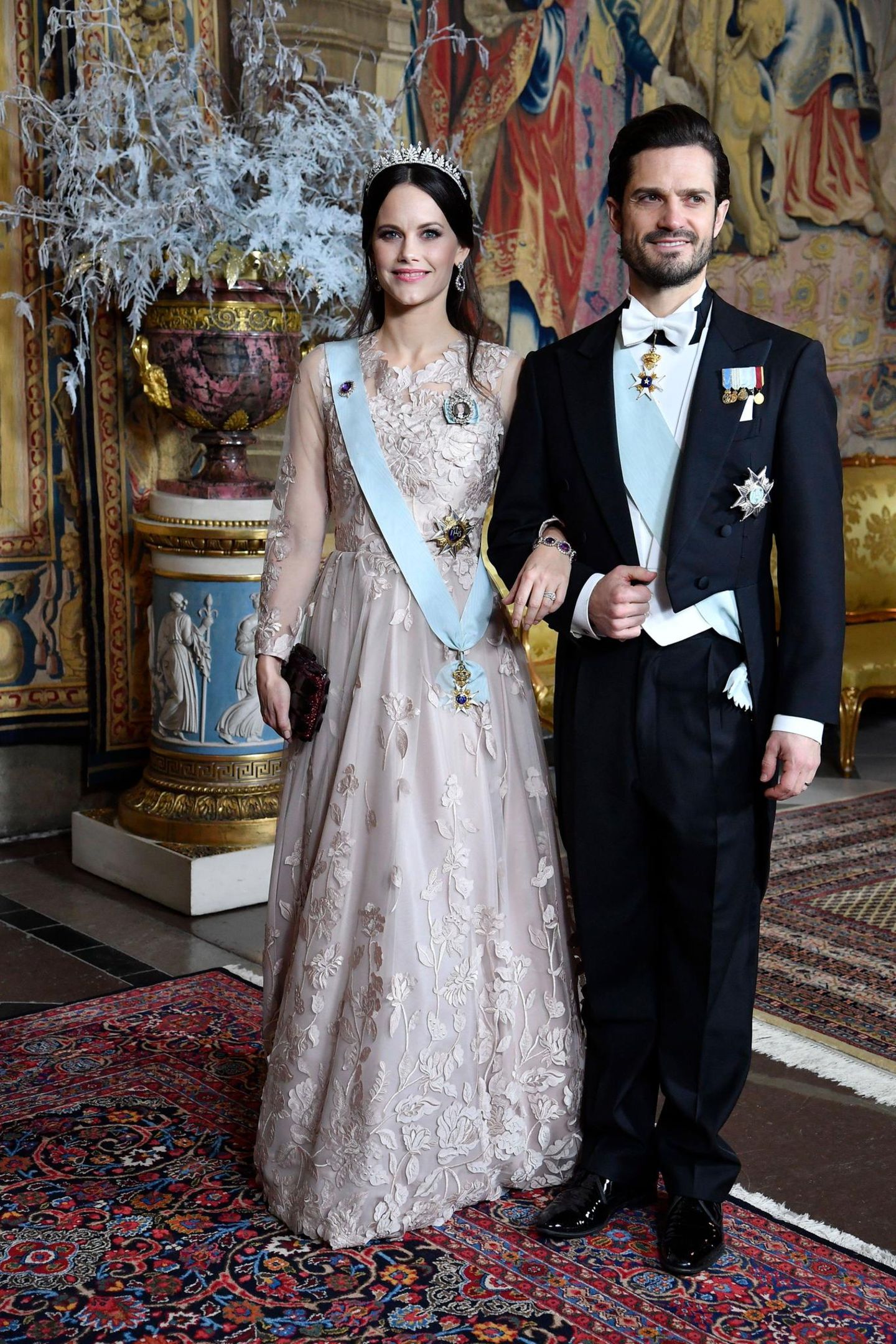 Beim Königsdinner zu Ehren der Nobelpreisträger im Schloss zeigt sich Prinzessin Sofia in einer blassrosa Traumrobe mit Blütenstickereien. Ihr dunkelbraunes Haar trägt sie halb hochgesteckt. 