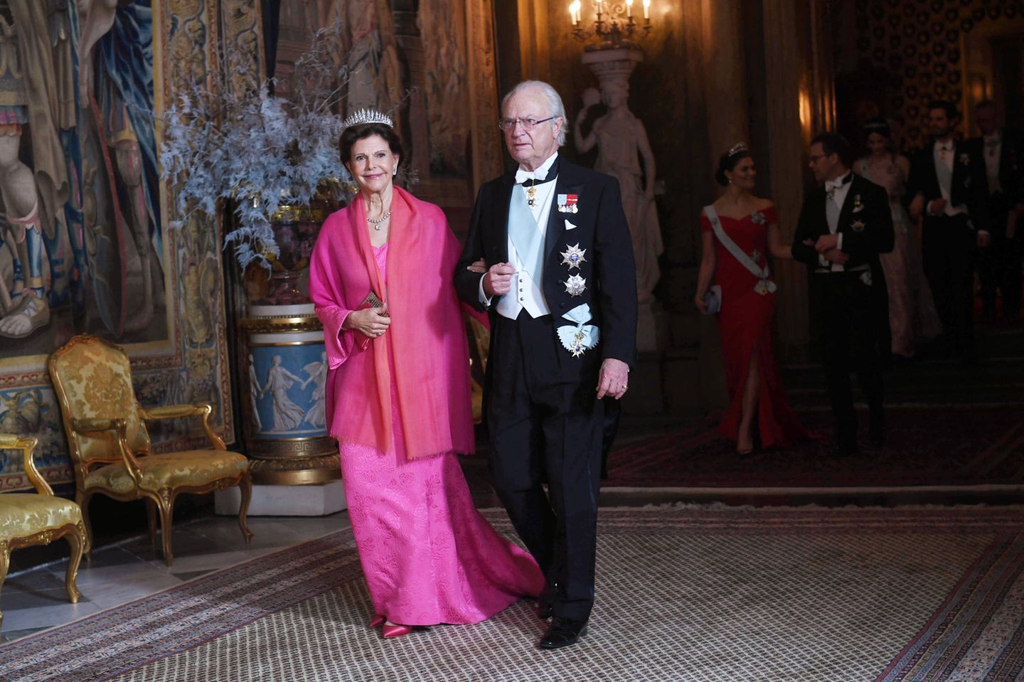 Auch Königin Silvia entscheidet sich für eine knallige Farbe. Sie kommt in einer pinken Robe mit farblich passender Stola. 