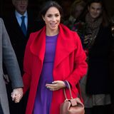 Meghan ist im farbenfrohen Outfit unterwegs und umfasst ihre Babykugel.