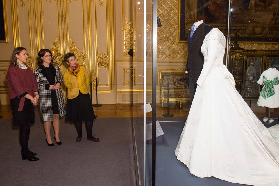 Stolz begutachtet Prinzessin Eugenie zusammen mit der Kuratorin und der Ausstellungsleiterin ihr Brautkleid auf Schloss Windsor. 