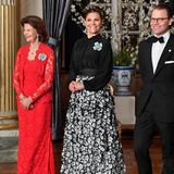 Beim Dinner für das schwedische Parlament macht sich Prinzessin Victoria besonders "gastgeber-fein". Zu einer schwarzen Bluse kombiniert sie einen Rock, der durch seine florale 3D-Optik und die Farbkontraste besonders ins Auge sticht. 