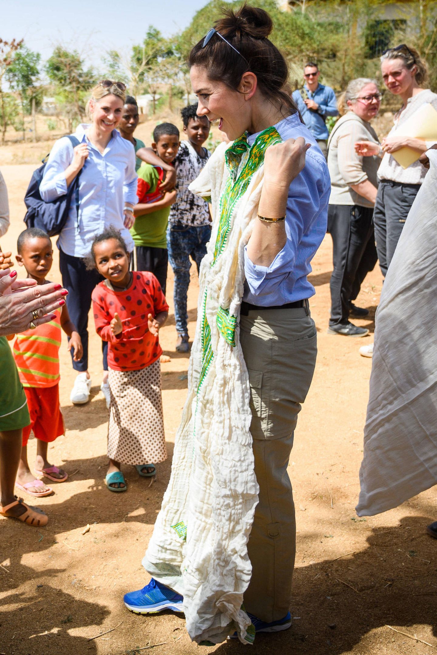 "Oder soll ich lieber dieses Kleid tragen?", scheint Prinzessin Mary die anwesenden Kinder im Flüchtlingscamp zu fragen. Die traditionelle Tracht in Weiß und Grün hätte ihr sicherlich gut gestanden.