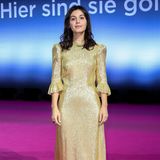 Sängerin Katie Melua trägt ein goldenes Kleid mit Rüschendetails. 