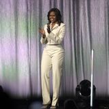 Funkelnde Fashionista: Zum weißen, angesagten Hosenanzug von Acne Studios trägt Michelle Obama spitze Glitzer-Pumps von Jimmy Choo, die perfekt zu ihren Broschen am Revers passen. 