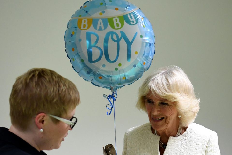 In Berlin wird Herzogin Camilla ein Geschenk und ein Luftballon für Baby Sussex überreicht.