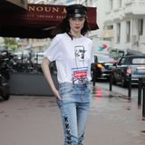 Coco Rocha setzt auf eine Jeans mit coolen Schleifendetails und ein bedrucktes Shirt aus der "SupremexGaultier"-Kollektion. Rote Lippen, derbe Boots und eine schwarze Schiebermütze geben dem Styling das gewisse Etwas. 