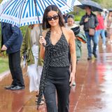 Lena Meyer-Landrut macht die verregneten Straßen Cannes' zu ihrem Laufsteg: Zu ihrem schwarzen Outfit und der XL-Sonnenbrille setzt sie mit einem blau-weiß gestreiften Schirm einen farblichen Akzent. 