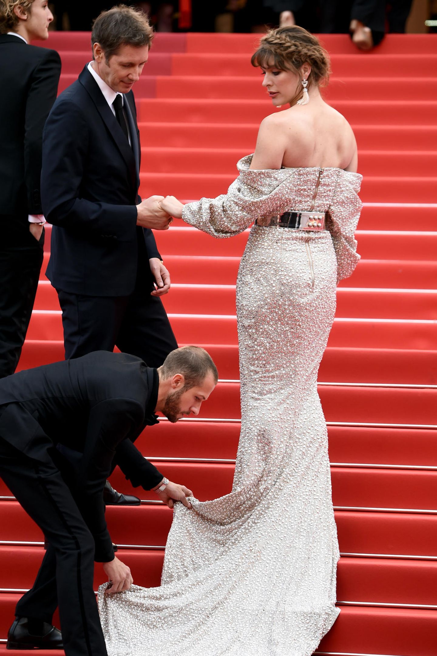 Die Treppen in Cannes haben es in sich. Auch Milla Jovovich benötigt Hilfe. Und das von gleich zwei Assistenten.