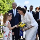 Ein kleines Mädchen überreicht Königin Silvia einen Strauß Blumen.