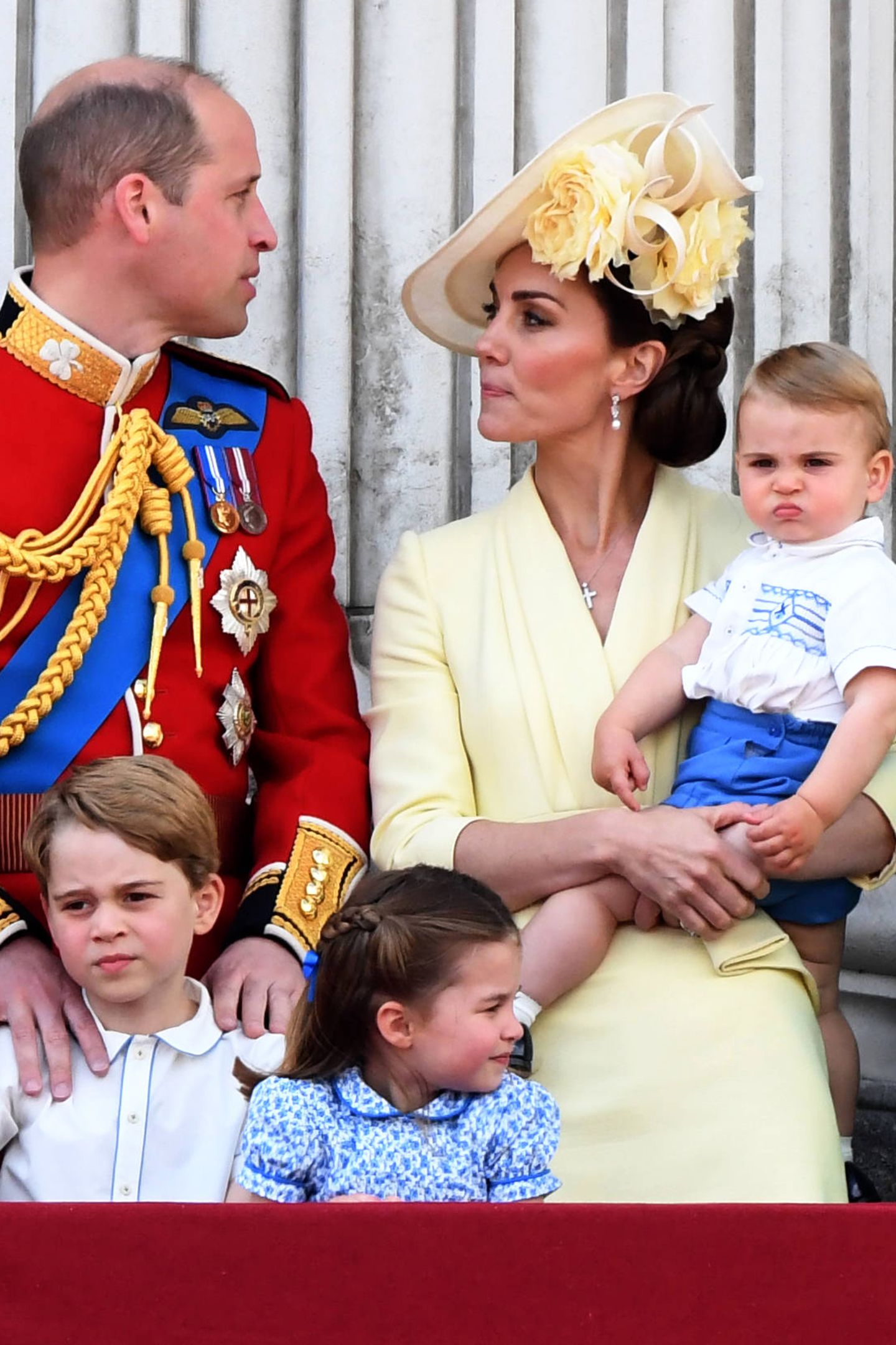 Ihre Haare trägt Catherine zu einem tiefen, seitlichen Dutt gestylt. Ihren Kopf ziert ein eleganter Hut mit Blüten, der farblich perfekt zu ihrem Kleid von Alexander McQueen passt. 