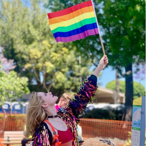 Auf der Pride Parade schwenkt sie eine große Regenbogenflagge.