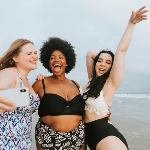 Shape Bikini, drei lachende Frauen in Bademode am Strand, die ein Selfie machen