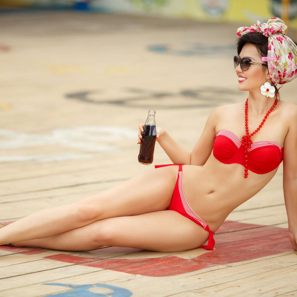 Retro-Bikini, Frau auf Holzboden im roten Bikini mit Getränk in der Hand