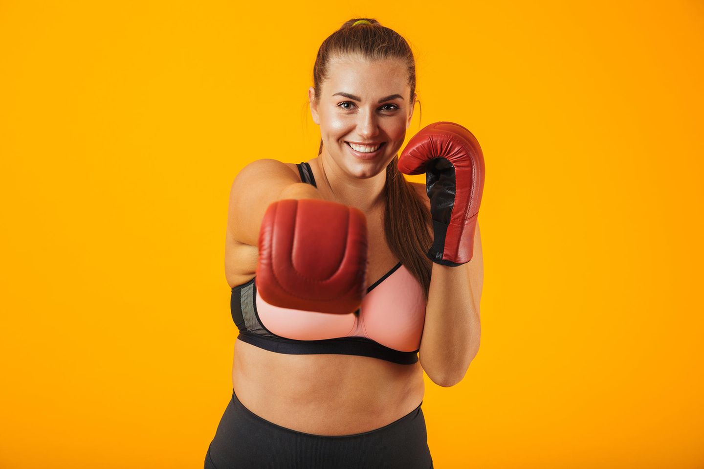 Sport-BH große Größen, junge Frau im Sport-BH trägt Boxhandschuhe