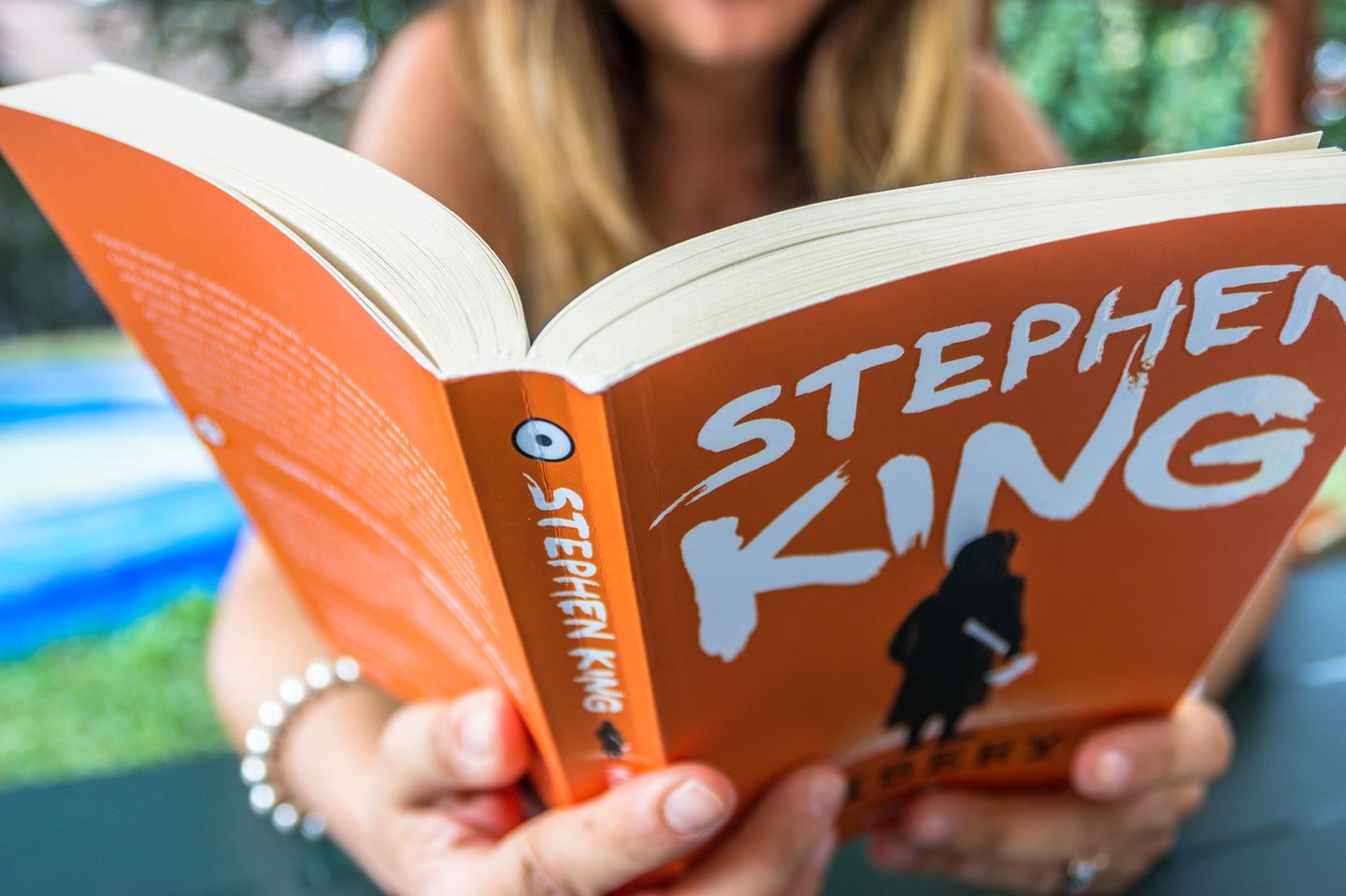Stephen-King-Buch, Frau liest in dem Buch "Misery" von Stephen King
