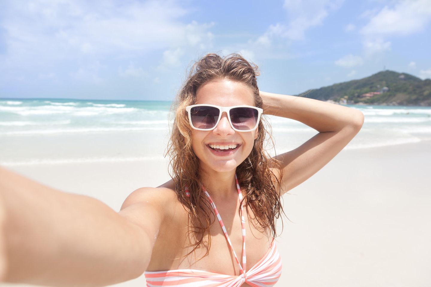 Junge Frau macht Selfie am Strand