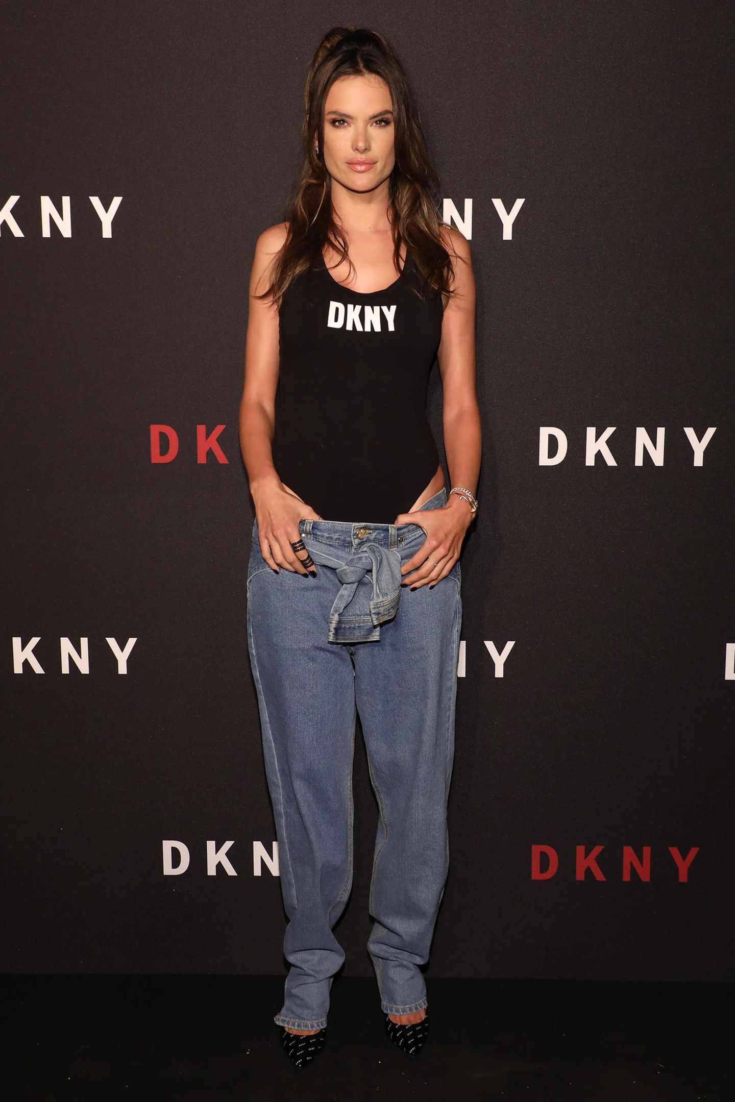 Alessandra Ambrosio trägt zu einer weiten Jeans mit coolen Knot-Details einen engen Bodysuit in Schwarz. 