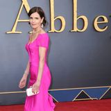 Auch Elizabeth McGovern strahlt in einer pinkfarbenen Robe mit Schleppe bei der Filmpremiere in London. Ein besonders schöner Kontrast: Die Schauspielerin wählt zum knalligen Kleid rote Pumps. 