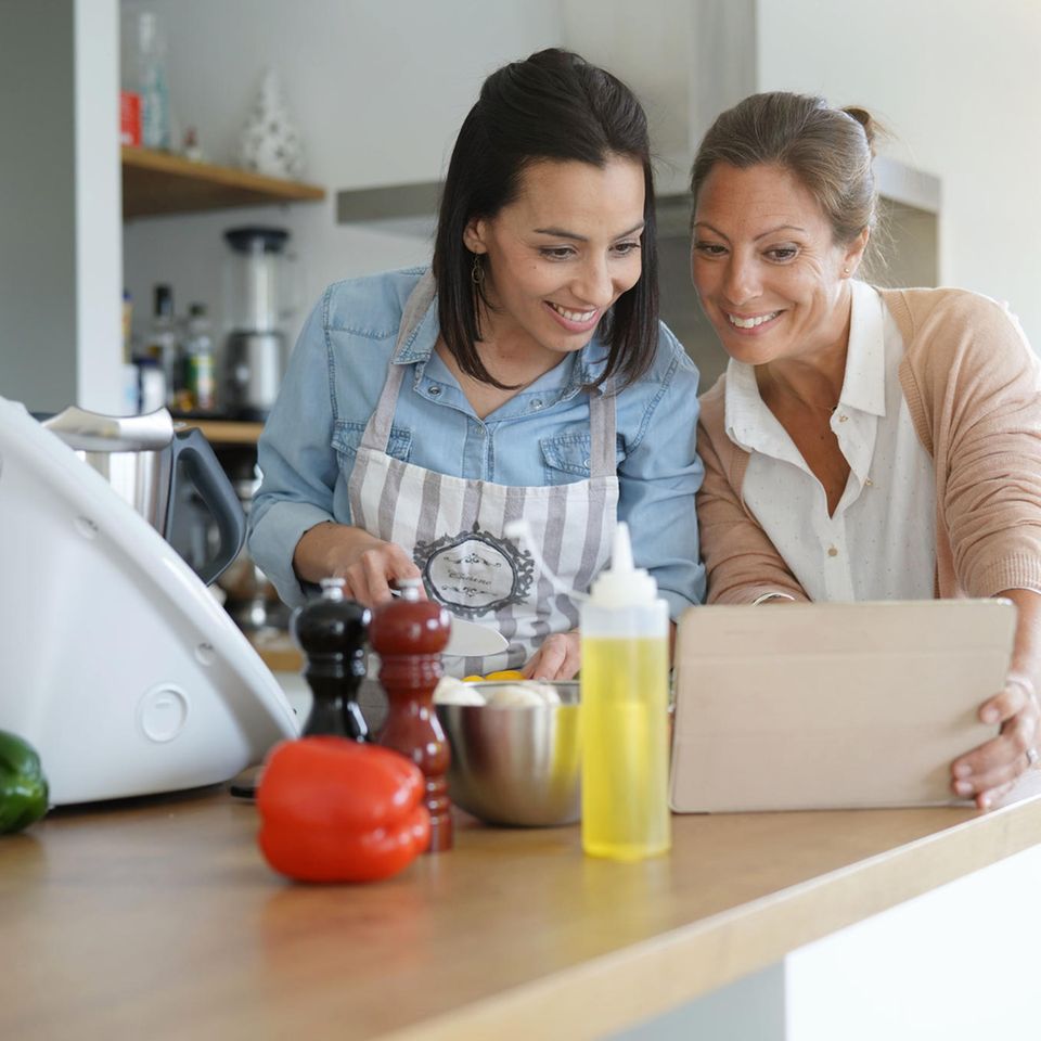 Thermomix-Alternative, Freundinnen lachen in der Küche, gucken auf Tablet-PC, kochen, Küchenmaschine