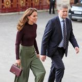 Catherine trägt einen hautengen, raffinierten Rollkragen-Pullover in einem Bourdeaux-Ton (von Warehouse, ca. 46 Euro). Dazu wählt die Herzogin eine weite Hose in Grüntönen, Pumps - ebenfalls in bordeauxrot und eine luxuriöse Handtasche von Chanel. 