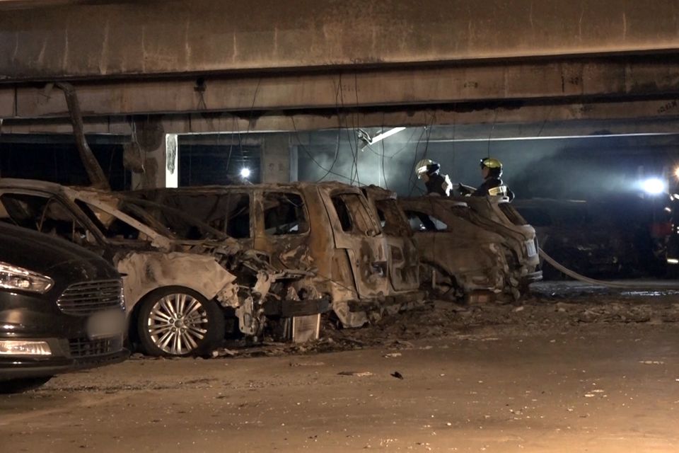 Feuerwehrmänner begutachten die ausgebrannten Autos im Parkhaus des Flughafens Münster Osnabrück.