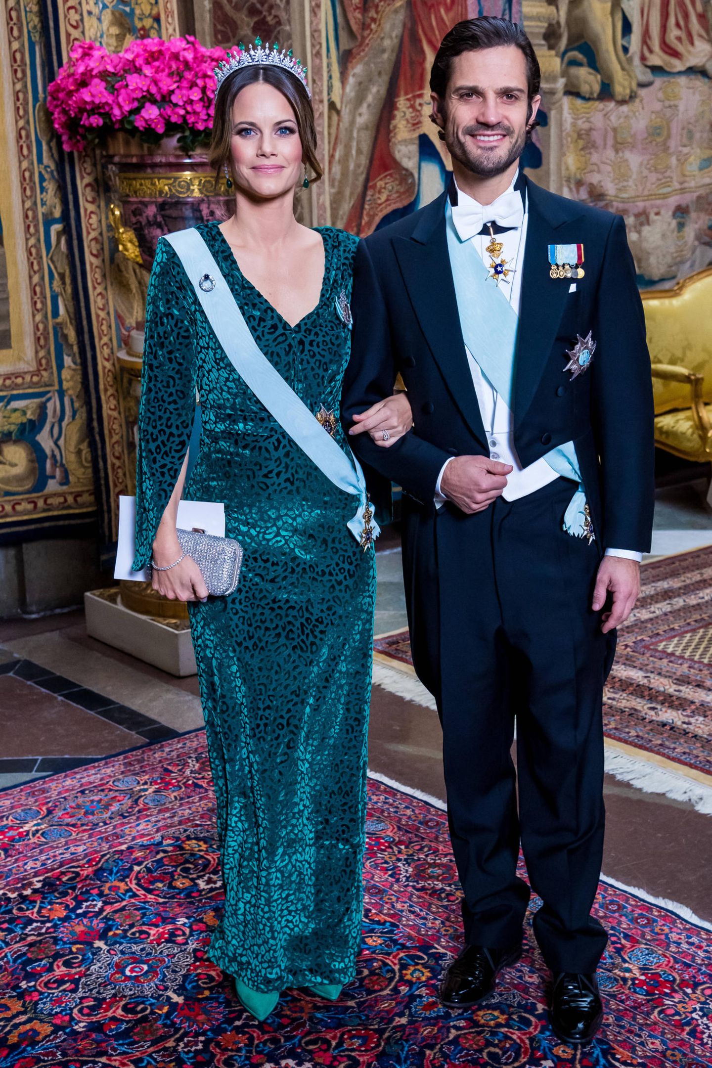 Beim offiziellen Dinner (auf schwedisch: Representationsmiddag) im königlichen Palast in ​Stockholm, erscheinen Prinz Carl Philip und Prinzessin Sofia in feierlicher Abendgarderobe. Die hübsche 34-Jährige zeigt sich in einem bodenlangen Samtkleid mit Leoparden-Muster und Cape-Schnitt des schwedischen Labels "By Malina". Dazu trägt sie eine funkelnde Tiara und eine Clutch mit Glitzerapplikationen. Die Kombination aus Samt und Strass sowie dem dezenten Leo-Muster des Kleids ist Sofia jedenfalls sehr gelungen.  