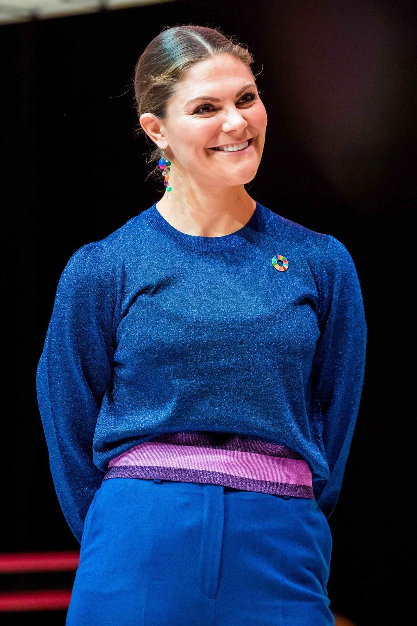 Zum Pep Forum im Karolinska-Institut in Stockholm erscheint Prinzessin Victoria wie bereits im letzten Jahr in einer royalblauen Kombination bestehend aus einem auffälligen Pullover mit Glitzer und farblich abgesetztem Bund sowie einer locker sitzenden Anzugshose mit weitem Schnitt. 