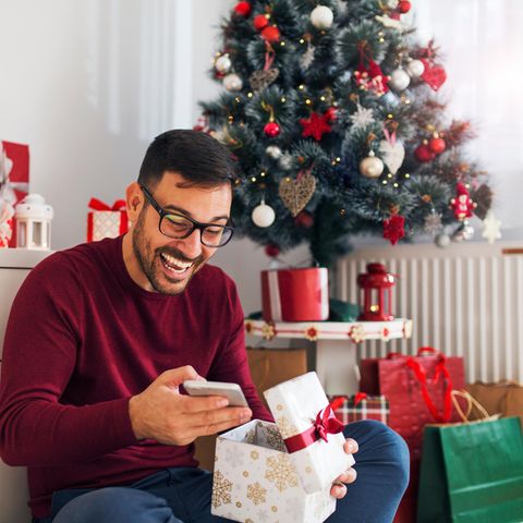 Weihnachtsgeschenke für Männer, Mann packt sein Geschenk aus und freut sich