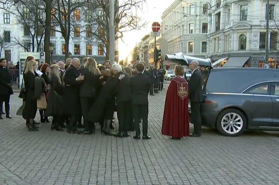 Ari Behns Angehörigen geleiten den Sarg zum Auto. Vertraut liegen sich die Trauernden in den Armen. Selbst König Harald umarmt die Anwesenden.