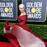 Schwungvoll schwebt Helen Mirren in tiefroter Robe von Christian Dior Haute Couture über den Red Carpet der Golden Globes.
