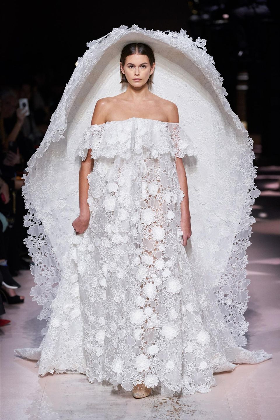 Ein ganz besonderes Highlight darf Kaia Gerber während der Haute Couture Fashion Show des Luxus-Labels Givenchy präsentieren. Zugegeben: Für das Hochzeitskleid mit Off-Shoulder-Ausschnitt, XXL-Cape und dreidimensionaler Blütenspitze muss die Braut in Spe eine Portion Mut aufbringen. 