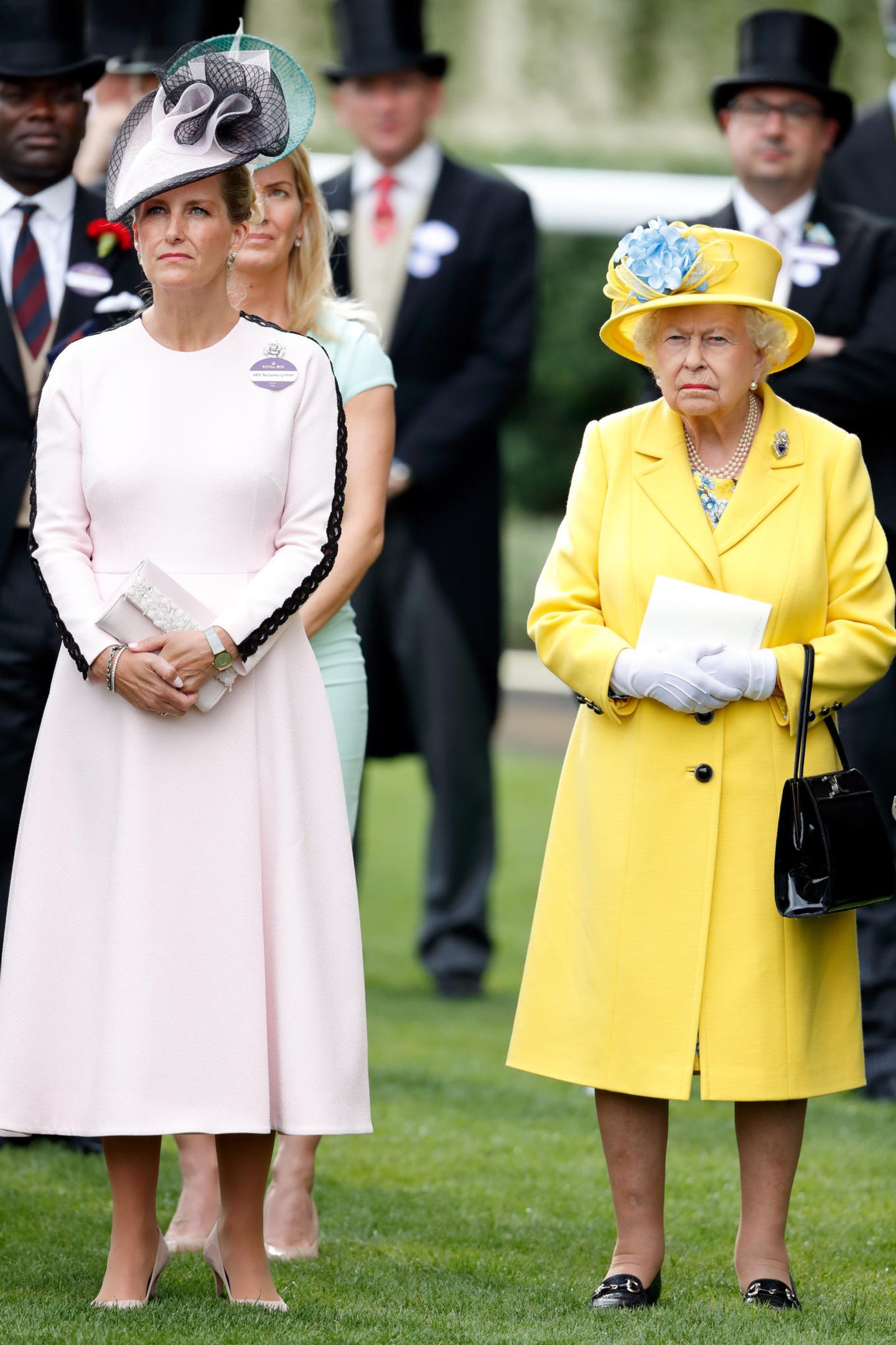 An Tag eins in Ascot 2018 entscheidet sich Gräfin Sophie für ein hellrosa wadenlanges Kleid, mit kunstvollen Applikationen am Ärmel. Ein passender farblicher Kontrast zu ihrer Schwiegermutter Queen Elisabeth, die sich für ein knalliges Zitronengelb entschieden hat. 