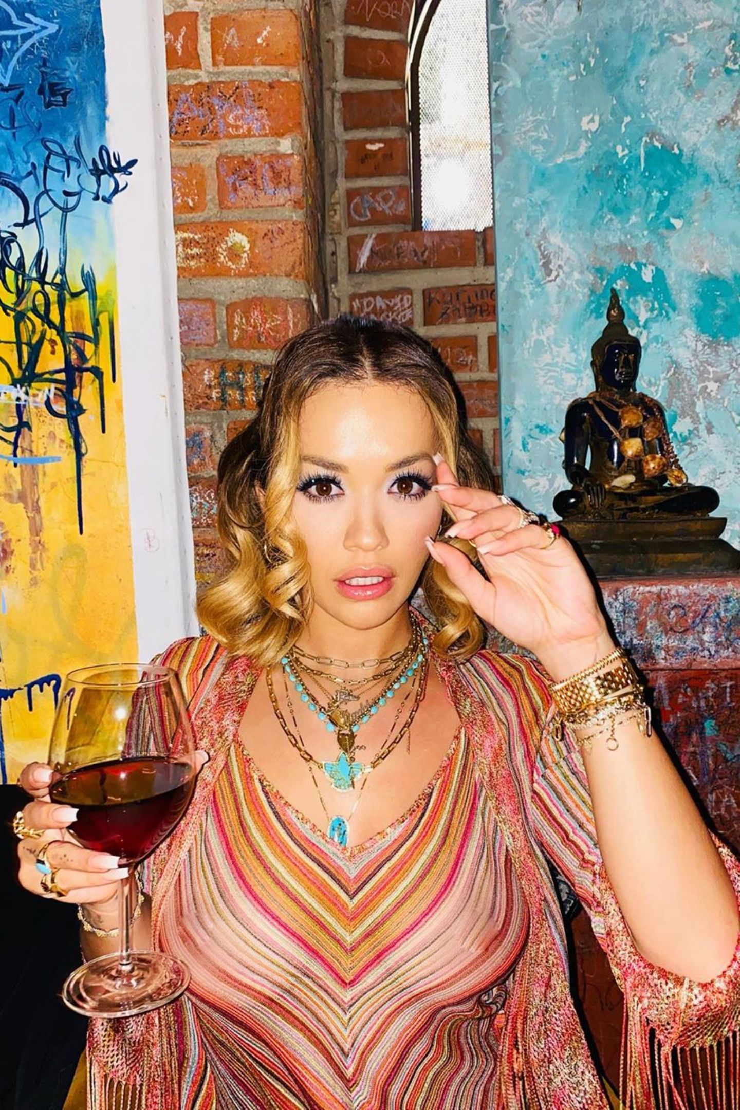 Rita Ora postet sich mit einem Gläschen Wein – da schaut aber kaum jemand hin, denn ihr transparentes Oberteil gibt mehr preis als es verdeckt.