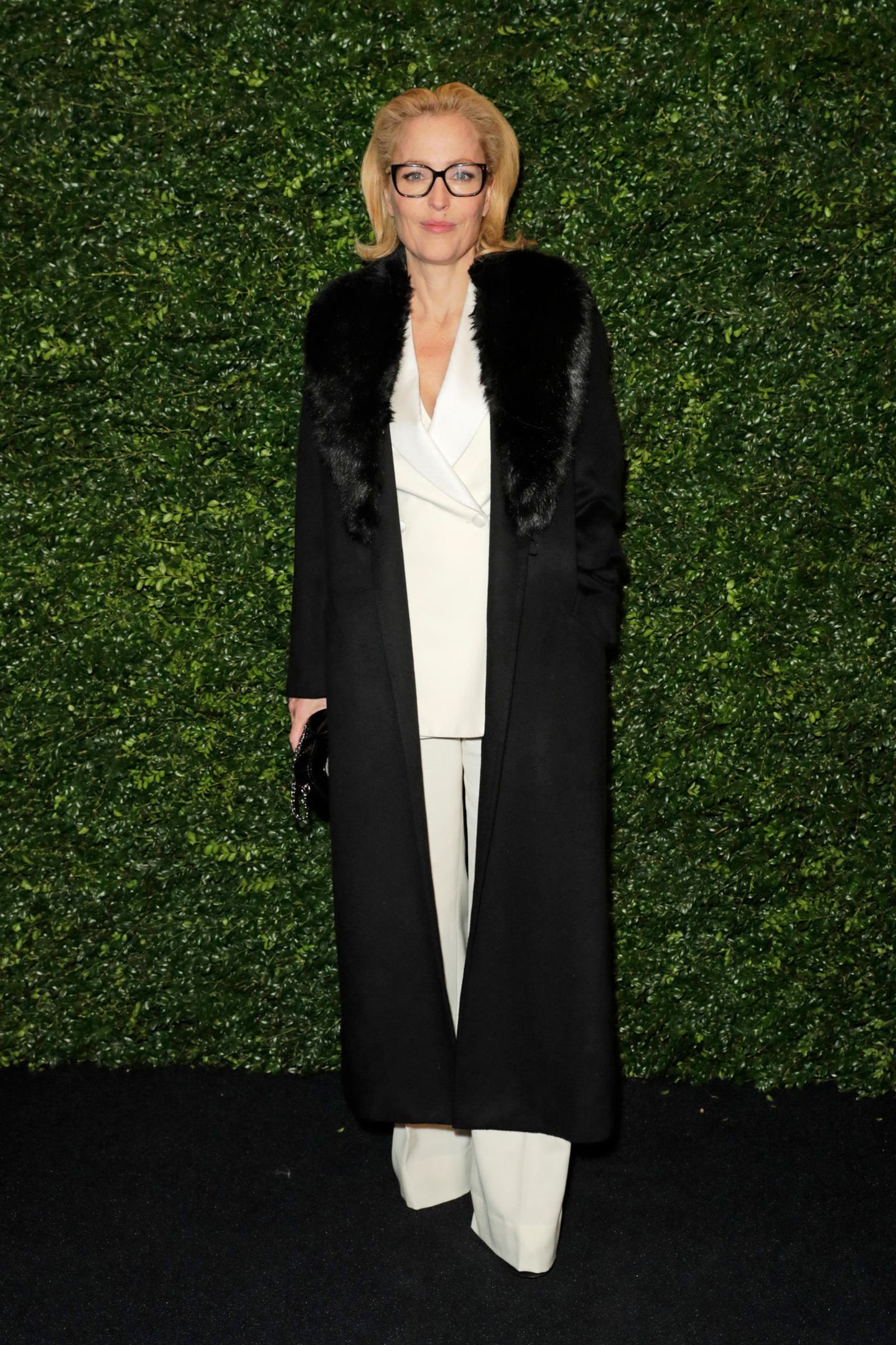 Gillian Anderson wählt einen hellen Zweiteiler zu dem sie einen schwarzen Mantel mit Fellkragen kombiniert. Die dunkle Brille und die glamourös geföhnten Haare sind ein zusätzlicher Eyecatcher! 