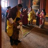 König Jigme  legt schützend die Hände auf die Schultern seines Sohnes Prinz Jigme Namgyel Wangchuck. Das Geburtstagskind schaut noch ein wenig skeptisch angesichts der beeindruckenden Zeremonie, der er beiwohnt.