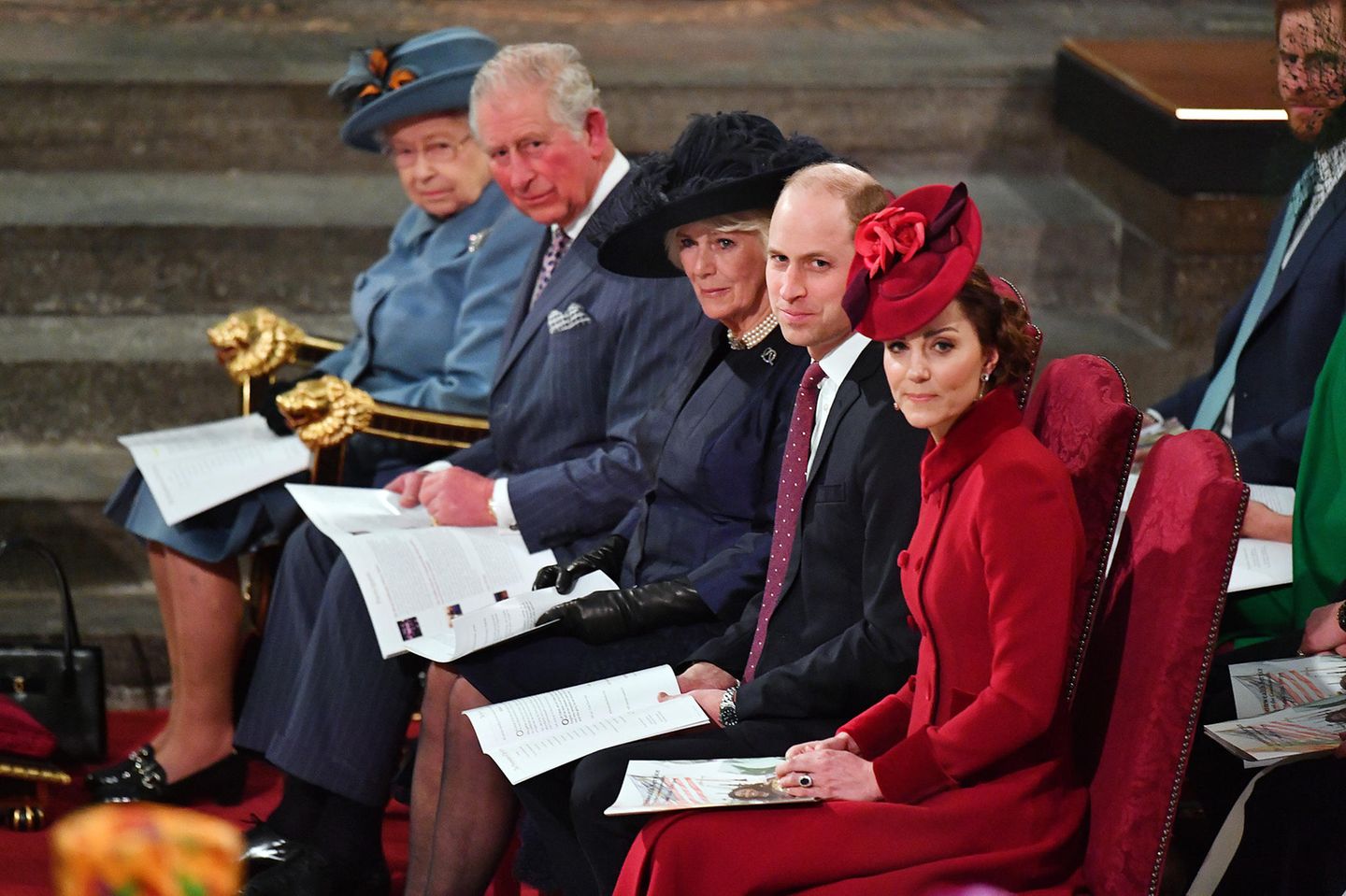 Die Queen als Oberhaupt der Familie Windsor sitzt ganz vorne in der ersten Reihe. Es folgten gemäß der Rangfolge im britischen Königshaus Prinz Charles, Herzogin Camilla, Prinz William und Herzogin Catherine. Harry und Meghan sitzen dahinter, in Reihe zwei.