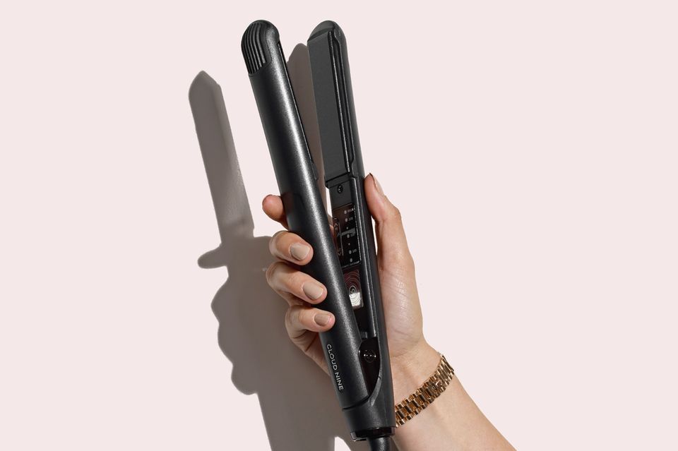 Frauenhand hält schwarzes, geöffnetes Glätteisen Frauenhand hält schwarzes, geöffnetes Glätteisen